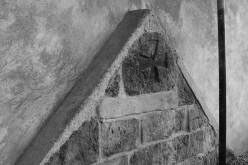 LIBČANY: detail kříže v podobě mělkého reliéfu v samém vrcholu románského západního štítu lodi. Stav v říjnu roku 2006 - po opravě kostela (foto M. Falta 2006).
